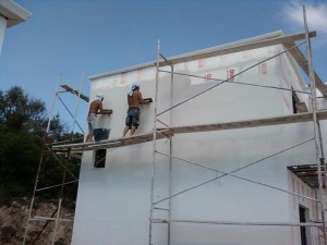 δύο εργαζόμενοι εφαρμόζουν επιληπτικό σε τοίχο σπιτιού που γίνεται εξωτερικη θερμομονωση